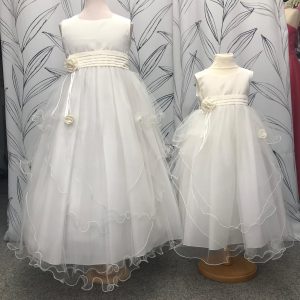 2 matching flower girl dresses with satin tops, tulle skirts and a pleated sash with a flower